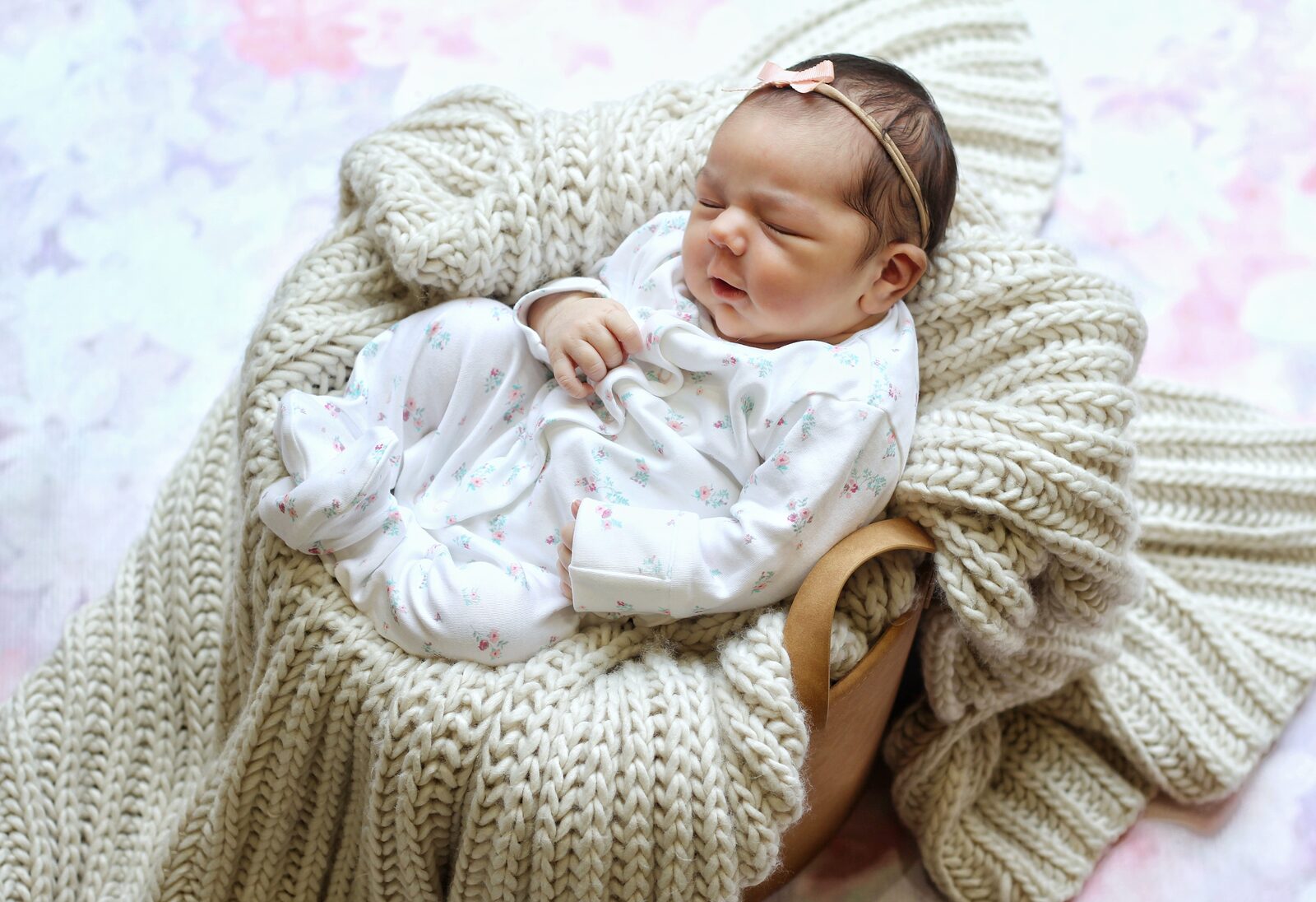 Newborn in a cream knit basket.